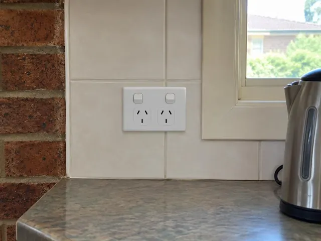 White double power point on tiled kitchen wall beside a window and brick column in Fennell Bay